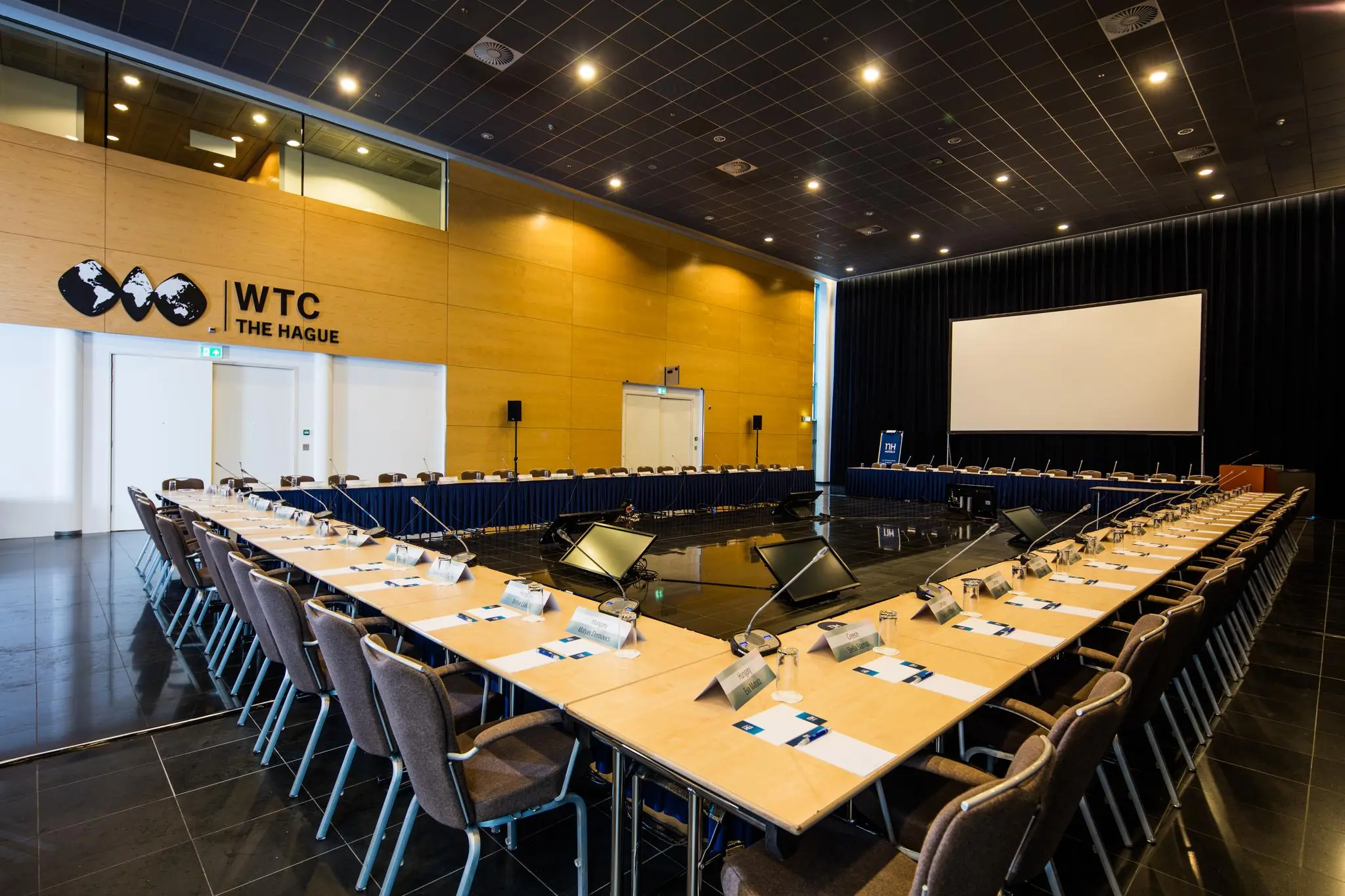 Conferentiezaal in het WTC The Hague aan de Prinses Beatrixlaan, ingericht voor een vergadering met microfoons en naamkaartjes.